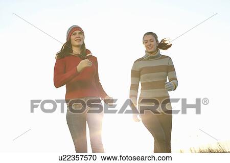 Stock Image - Women running together outdoors. Fotosearch