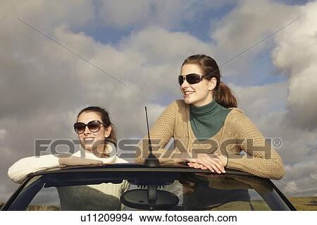 Picture - Women standing up in convertible. Fotosearch