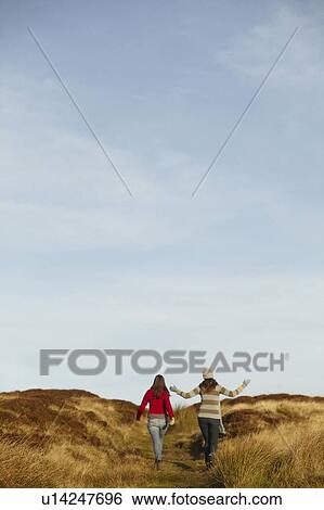 Women walking together on dirt path View Large Photo Image Stock Photograph - Women walking together on dirt path. Fotosearch