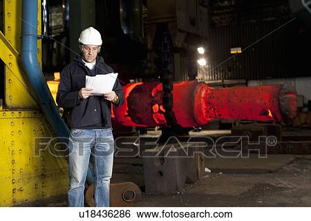 Worker reading papers in steel forge View Large Photo Image Stock Photograph - Worker reading papers in steel forge. Fotosearch