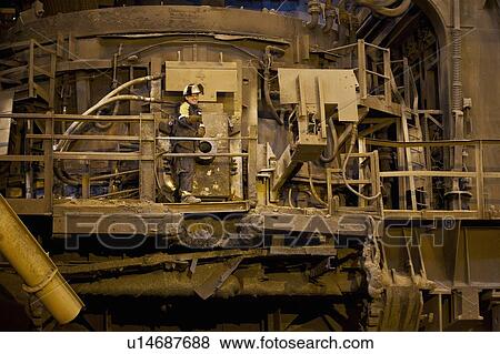Stock Photo - Worker using machinery in steel forge. Fotosearch