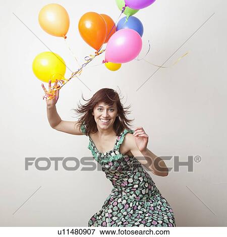Stock Photo - Attractive young woman playing with colorful balloons. Fotosearch