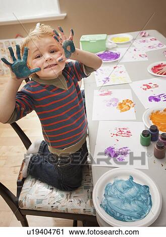 Stock Image - Boy (4-5) with paint covered hands. Fotosearch