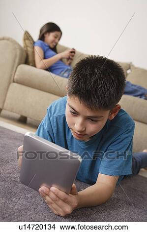 Boy using iPad lying on floor View Large Photo Image Picture - Boy using iPad lying on floor. Fotosearch