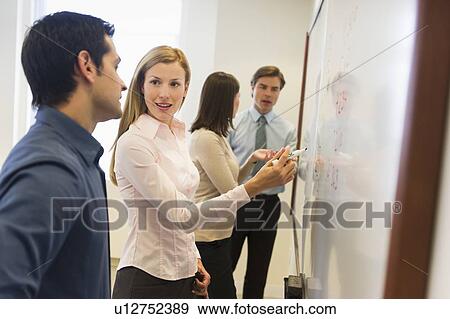 Business people writing at whiteboard View Large Photo Image Stock Photo - Business people writing at whiteboard. Fotosearch