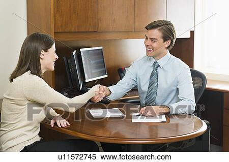 Businessman and client shaking hands in office View Large Photo Image Stock Photography - Businessman and client shaking hands in office. Fotosearch