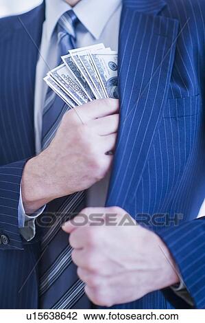 Stock Image - Businessman hiding banknotes in pocket. Fotosearch