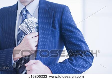 Stock Image - Businessman hiding banknotes in pocket. Fotosearch