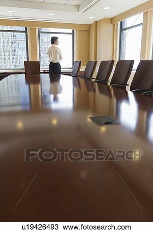 Stock Image - Businessman standing in board room. Fotosearch