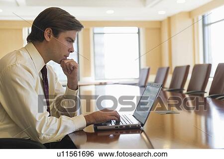 Stock Photograph - Businessman using laptop in board room. Fotosearch