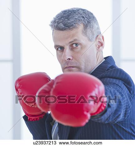 Stock Image - Businessman wearing red boxing gloves. Fotosearch