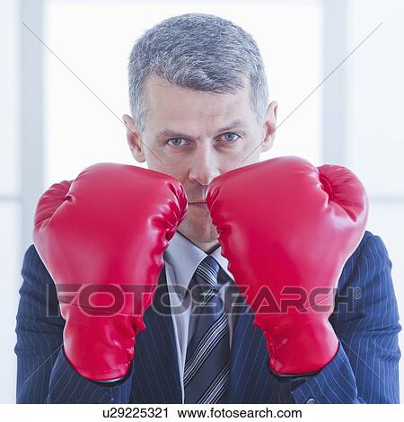 Stock Image - Businessman wearing red boxing gloves. Fotosearch
