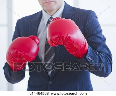 Stock Photo - Businessman wearing red boxing gloves. Fotosearch