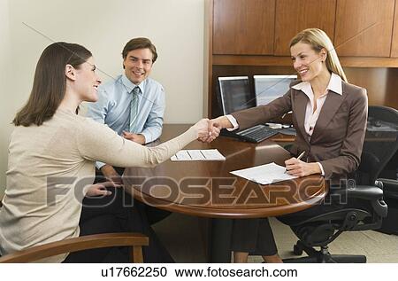 Businesswoman and clients shaking hands in office View Large Photo Image Stock Image - Businesswoman and clients shaking hands in office. Fotosearch