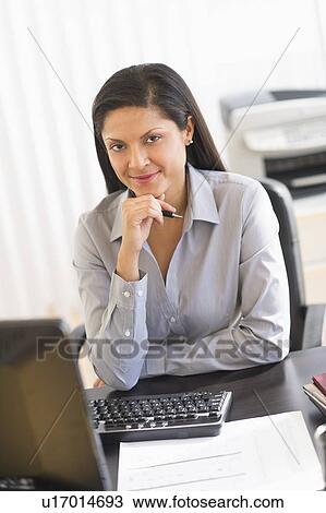 Businesswoman sitting at desk, portrait View Large Photo Image Stock Image - Businesswoman sitting at desk, portrait. Fotosearch