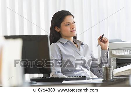 Stock Image - Businesswoman sitting at desk. Fotosearch