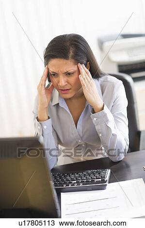 Stock Image - Businesswoman sitting at desk. Fotosearch