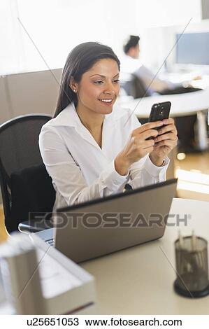 Businesswoman text messaging, businessman in background View Large Photo Image Stock Image - Businesswoman text messaging, businessman in background. Fotosearch