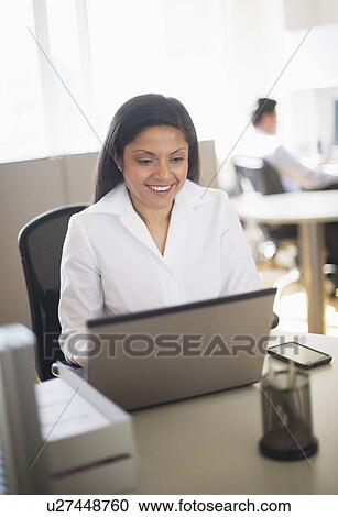 Businesswoman working on laptop, businessman in background View Large Photo Image Stock Image - Businesswoman working on laptop, businessman in background. Fotosearch