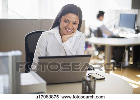 Businesswoman working on laptop, businessman in background View Large Photo Image Stock Photography - Businesswoman working on laptop, businessman in background. Fotosearch