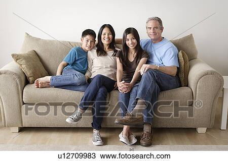 Cheerful family sitting on sofa View Large Photo Image Stock Image - Cheerful family sitting on sofa. Fotosearch