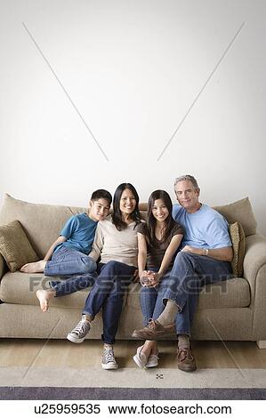 Stock Photography - Cheerful family sitting on sofa. Fotosearch