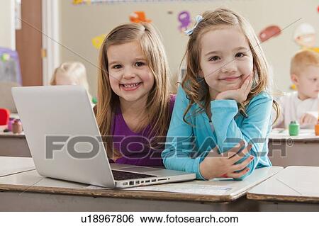 Stock Photograph - Children (4-5, 6-7) at school using laptop. Fotosearch