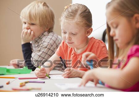 Stock Image - Children (4-5) drawing in kindergarten. Fotosearch