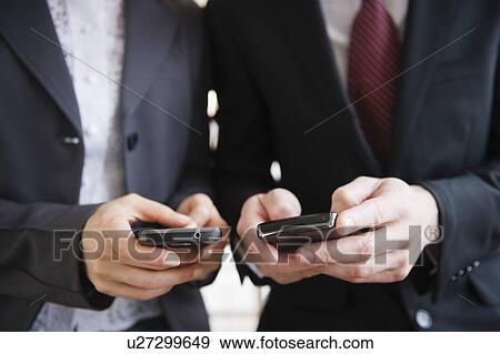 Stock Photo - Close up of business people's hand texting on mobile phones. Fotosearch