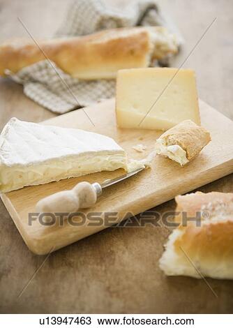 Stock Image - Close up of cheese and baguette on table, studio shot. Fotosearch