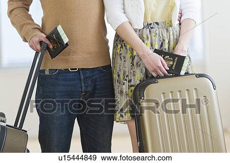 Stock Photo - Close up of couple with luggage and passports. Fotosearch