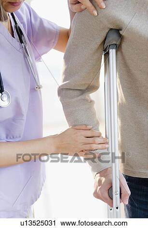 Close up of female doctor helping patient with crutch View Large Photo Image Stock Image - Close up of female doctor helping patient with crutch. Fotosearch