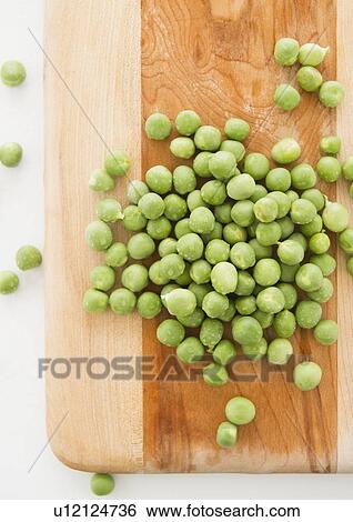 Stock Photograph - Close up of green peas on cutting board, studio shot. Fotosearch
