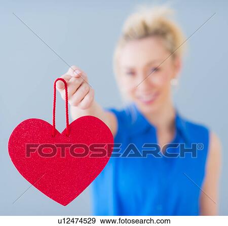 Close up of hand of young woman holding red heart, studio shot View Large Photo Image Stock Photo - Close up of hand of young woman holding red heart, studio shot. Fotosearch