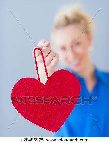 Close up of hand of young woman holding red heart, studio shot View Large Photo Image Stock Photography - Close up of hand of young woman holding red heart, studio shot. Fotosearch