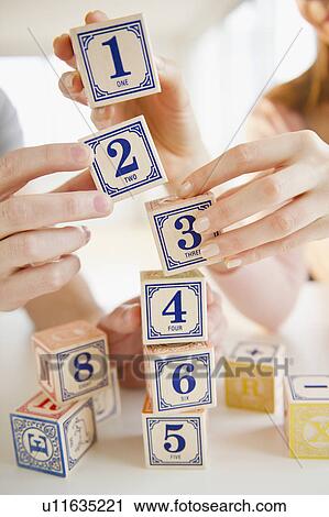 Close up of man's and woman's hands arranging blocks with numbers View Large Photo Image Stock Image - Close up of man's and woman's hands arranging blocks with numbers. Fotosearch