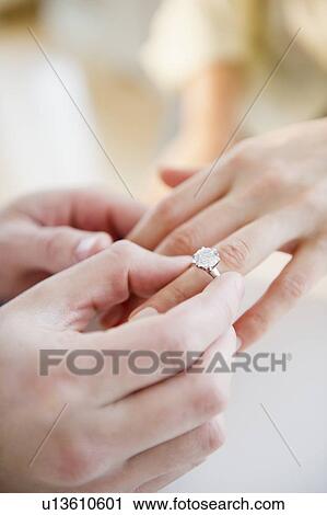Stock Image - Close up of man's and woman's hands with engagement ring. Fotosearch