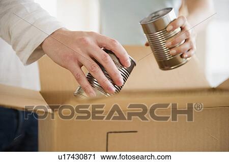 Close up of man's and woman's hands packing cans into box, studio shot View Large Photo Image Stock Image - Close up of man's and woman's hands packing cans into box, studio shot. Fotosearch