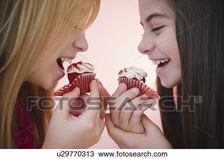 Close up of two girls eating cupcakes View Large Photo Image Stock Image - Close up of two girls eating cupcakes. Fotosearch