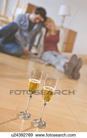 Stock Photo - Close up of wine glasses on floor with couple behind. Fotosearch