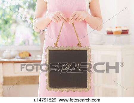Close up of young woman in apron holding open sign View Large Photo Image Stock Photo - Close up of young woman in apron holding open sign. Fotosearch