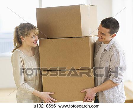 Couple carrying cardboard boxes during relocation View Large Photo Image Stock Photograph - Couple carrying cardboard boxes during relocation. Fotosearch