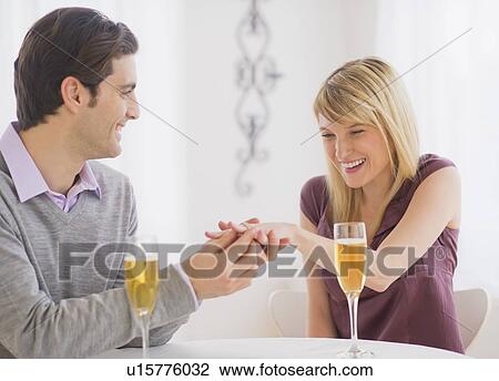 Stock Image - Couple celebrating engagement in restaurant. Fotosearch