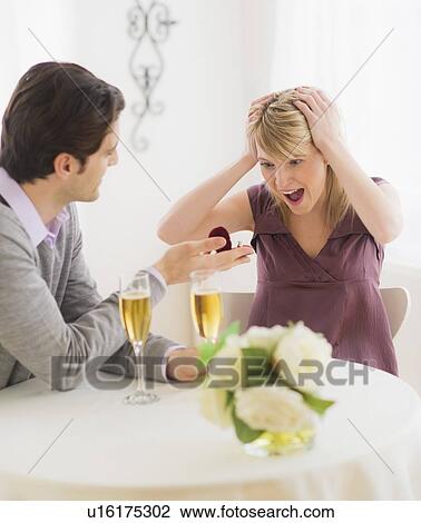 Stock Image - Couple celebrating engagement in restaurant. Fotosearch