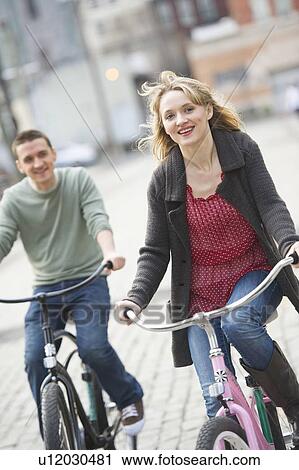 Stock Image - Couple cycling on street. Fotosearch