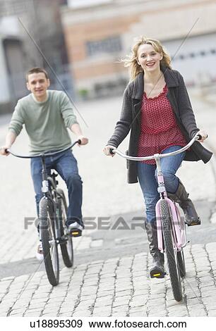 Couple cycling on street View Large Photo Image Stock Photo - Couple cycling on street. Fotosearch