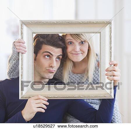 Couple holding picture frame and making faces View Large Photo Image Stock Photo - Couple holding picture frame and making faces. Fotosearch
