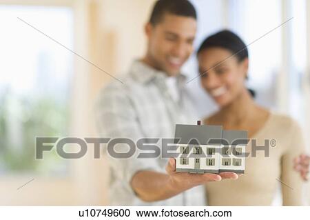 Stock Image - Couple holding toy house. Fotosearch