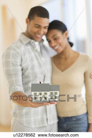 Stock Image - Couple holding toy house. Fotosearch