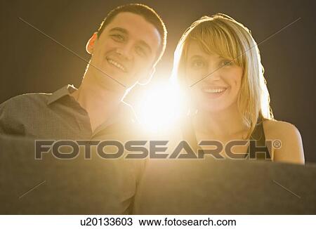 Stock Image - Couple in cinema with light behind. Fotosearch